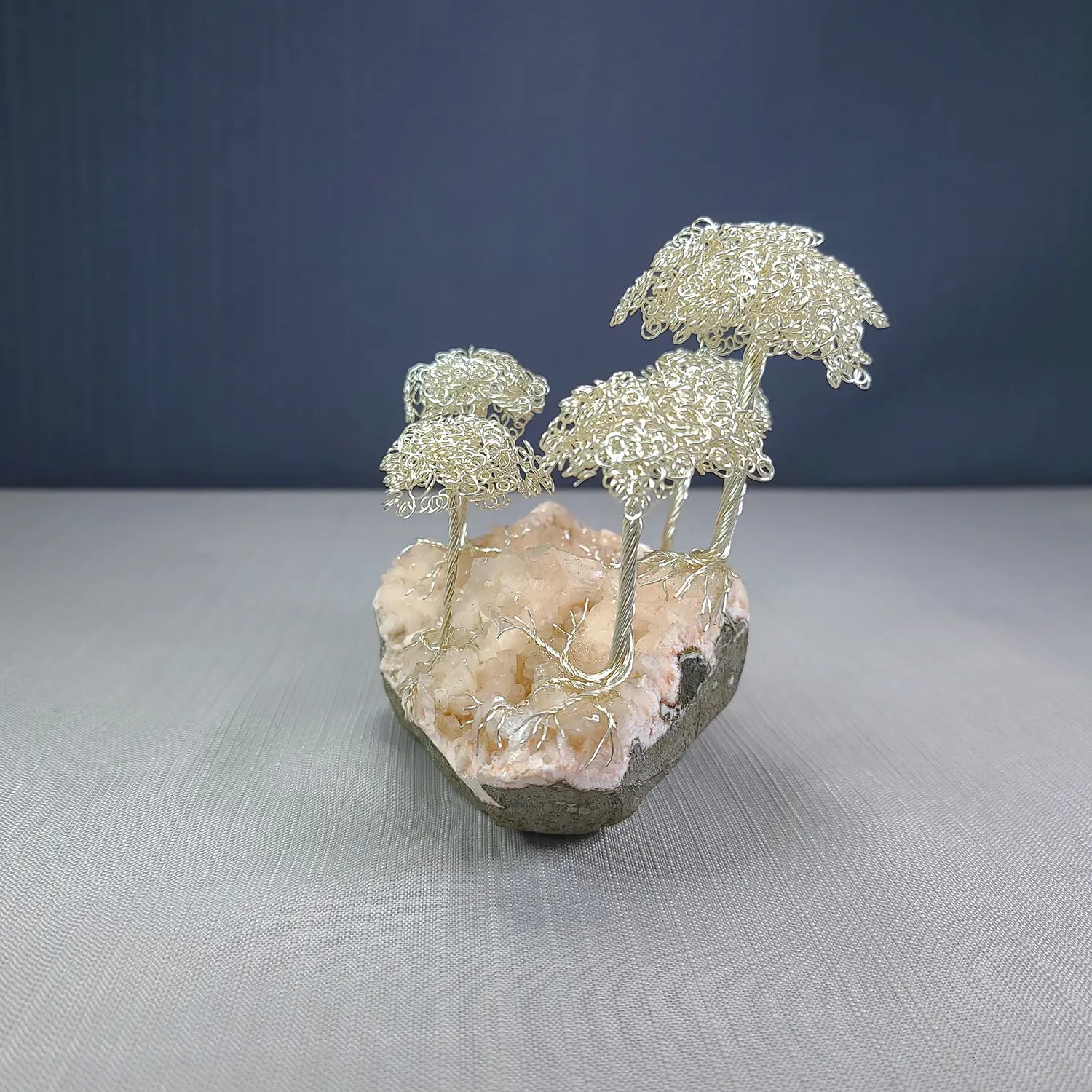 Decorative sculpture of wire trees on a rock with a blue background