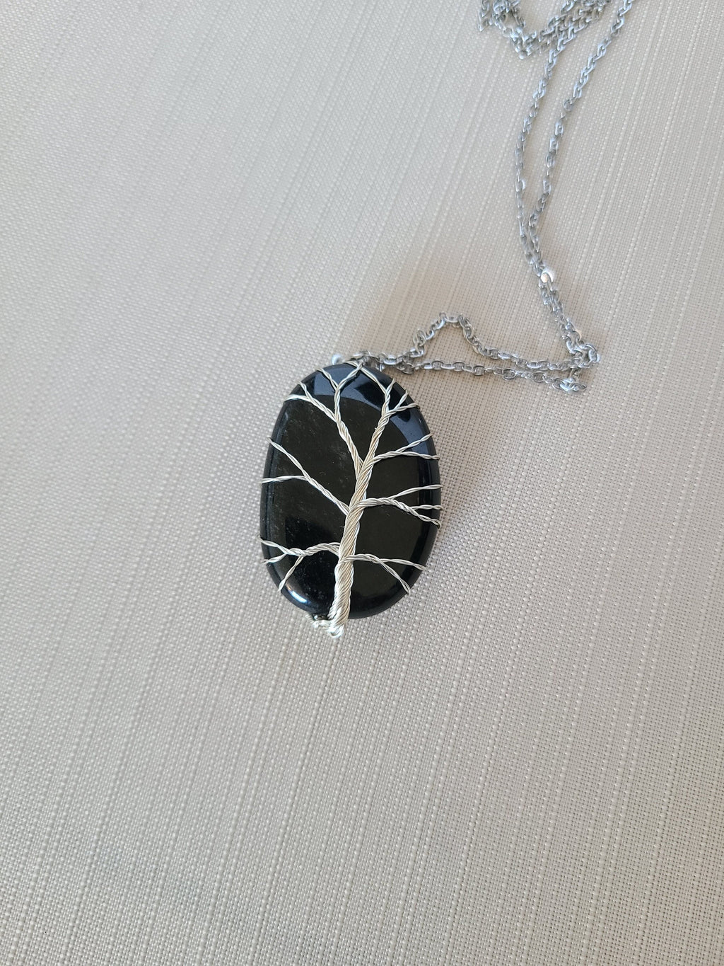Necklace with a tree-shaped pendant on a light gray background
