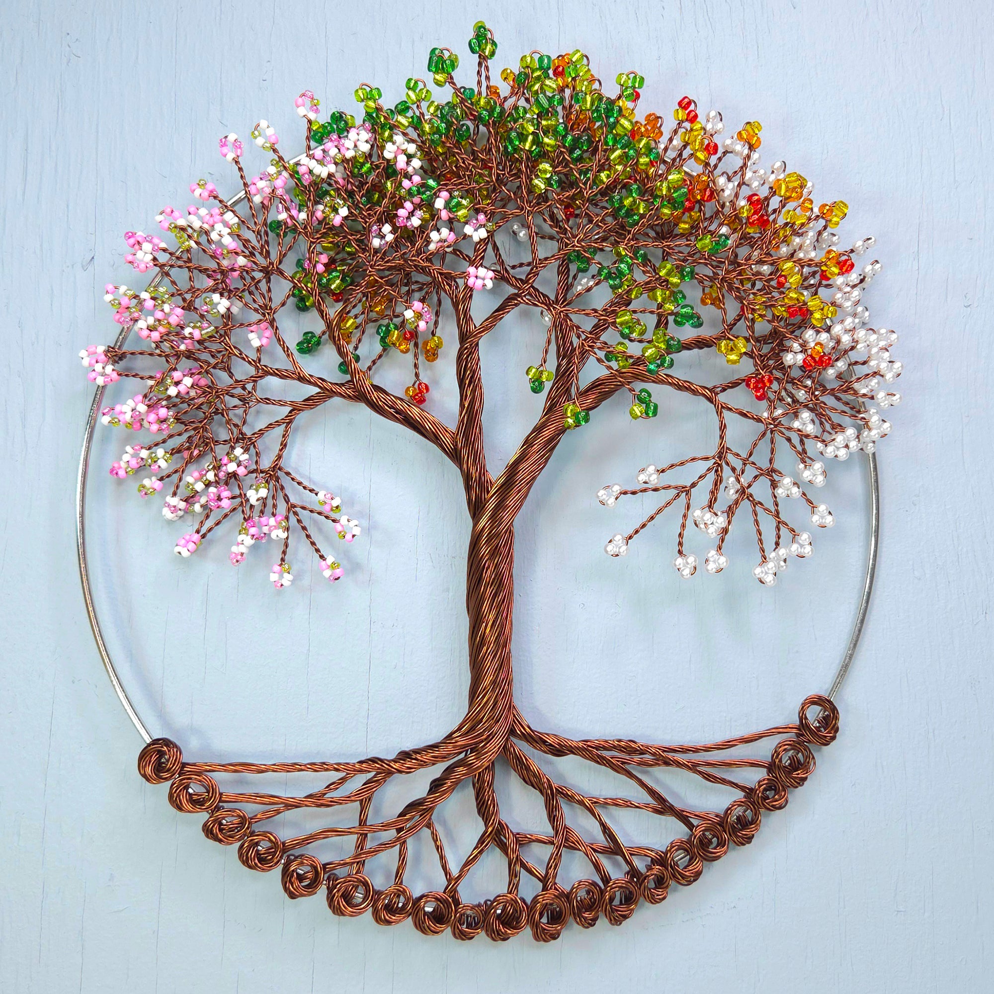 Decorative wall art of a tree with colorful beads on a light blue background