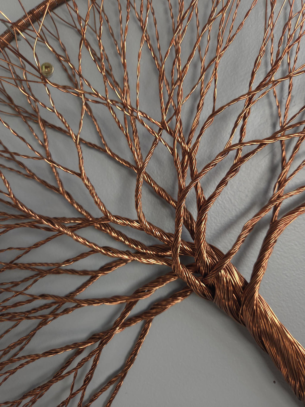 Bronze wire tree sculpture on a gray background