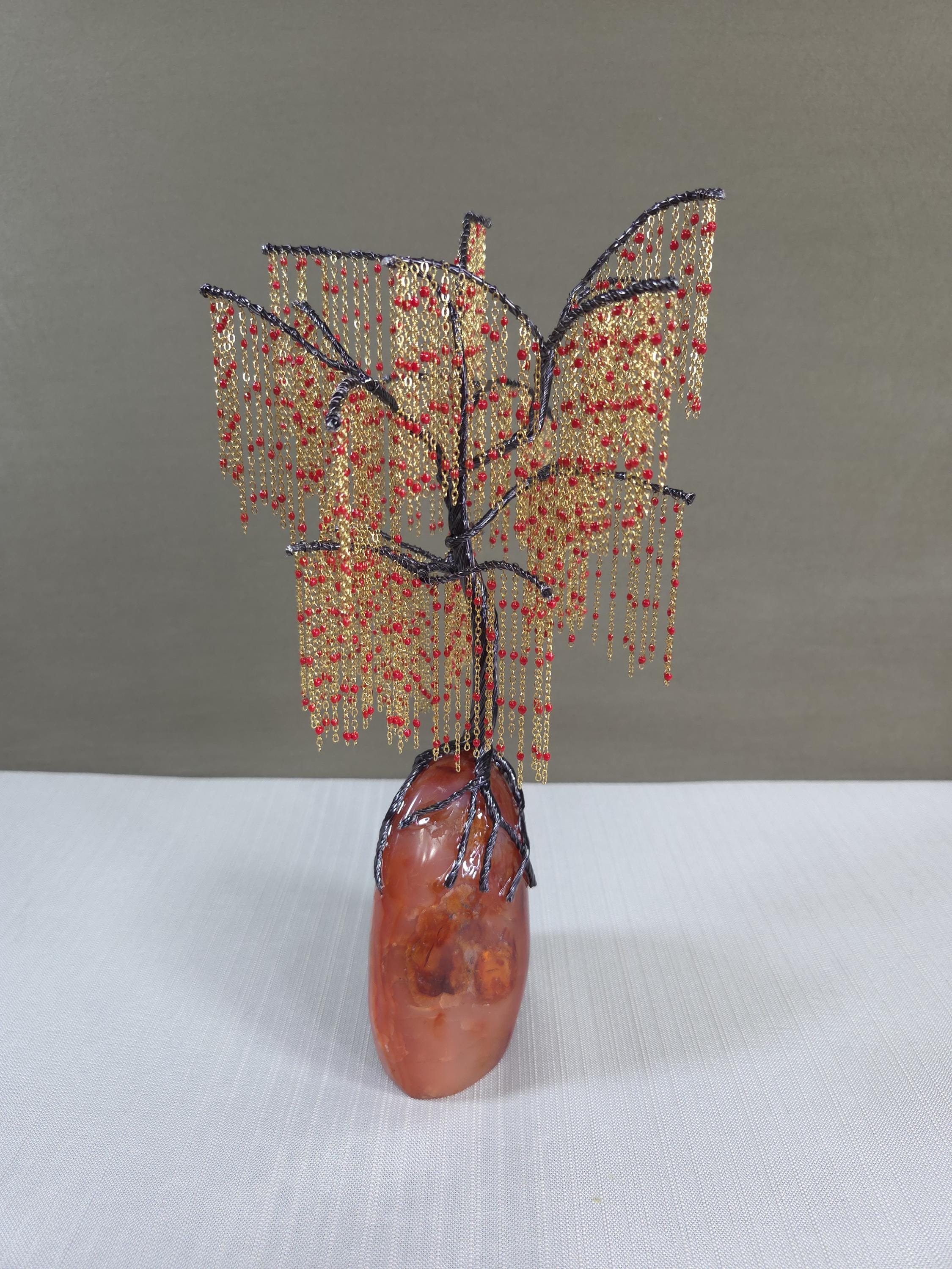 Decorative willow sculpture with bead details on a plain background