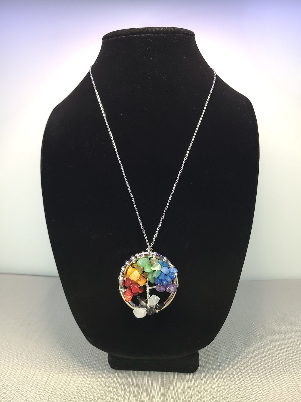 Necklace with a colorful pendant on a black bust against a white background