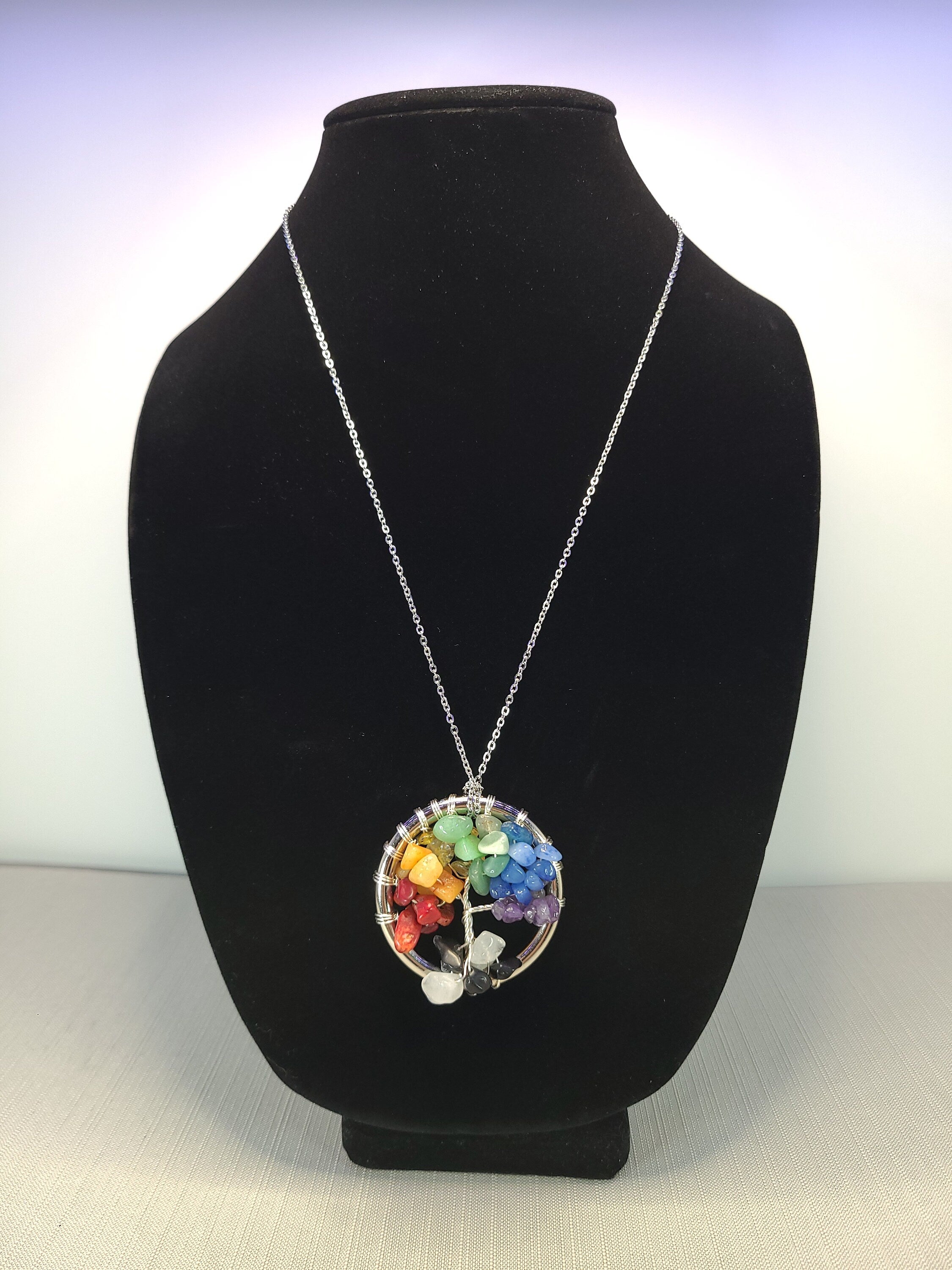 Necklace with a colorful pendant on a black bust against a white background
