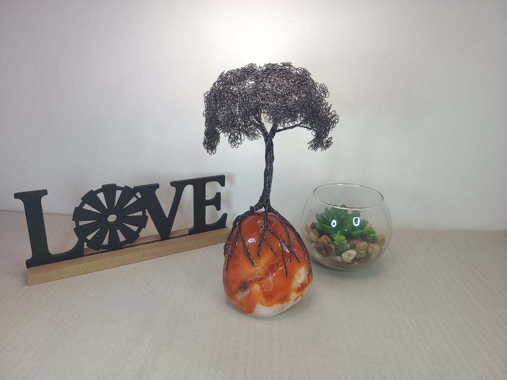 Decorative items including a tree sculpture, 'LOVE' sign, and small glass container on a plain background