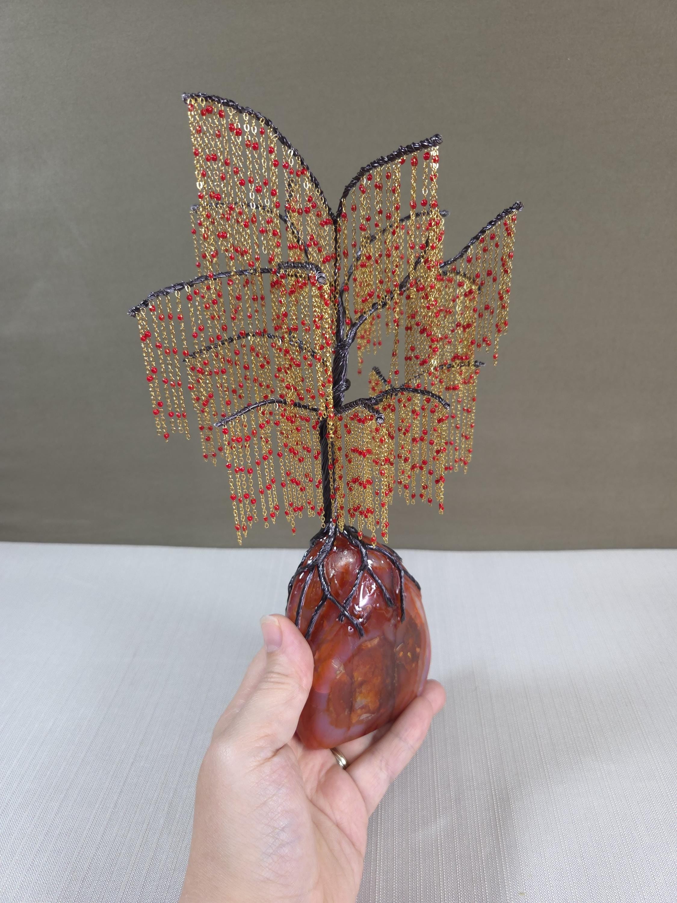 Hand holding a beaded willow sculpture on a neutral background