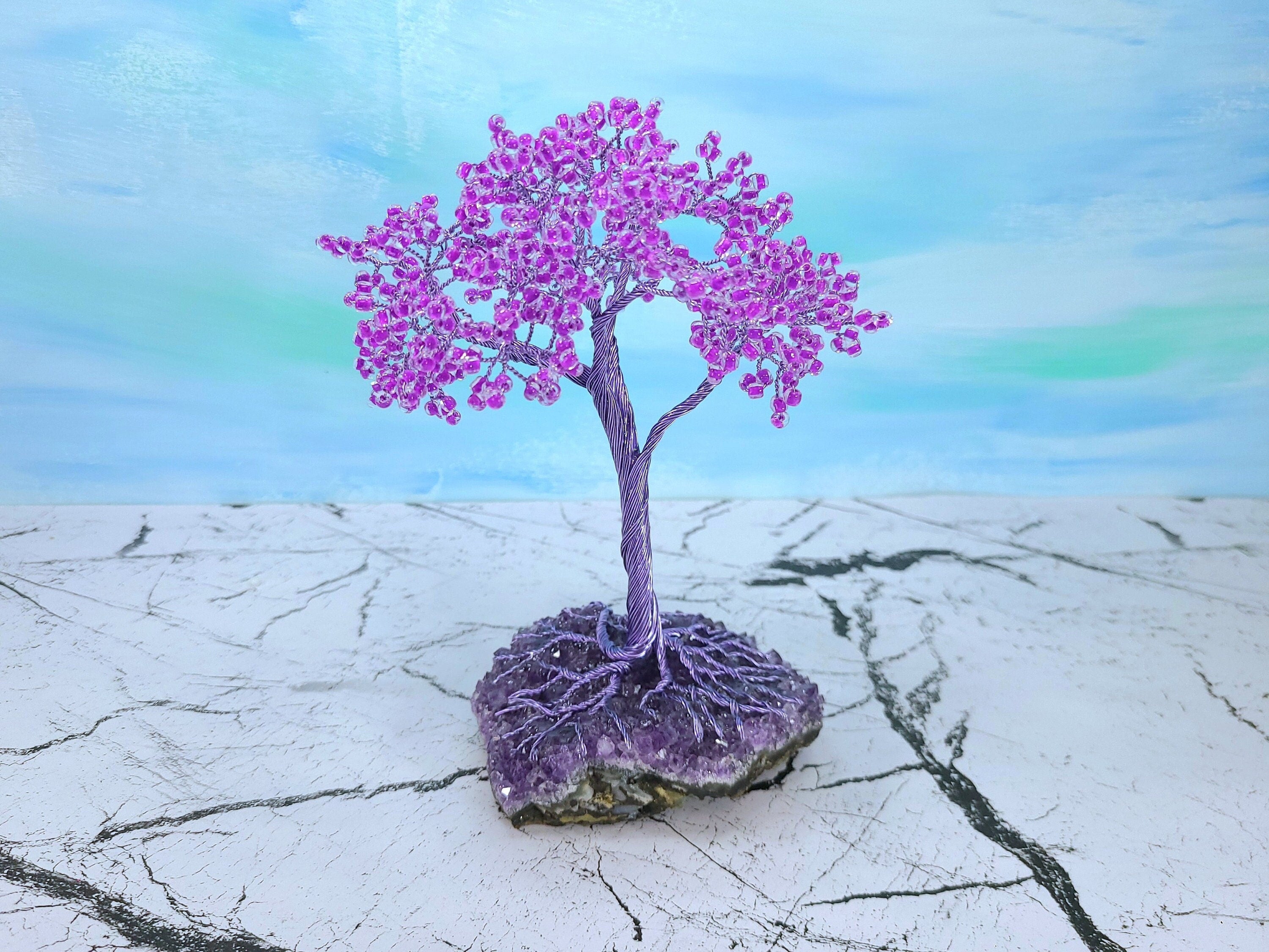 Purple tree with pink flowers on a cracked surface with a blue and green gradient background