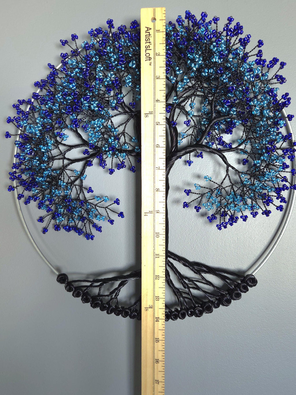 Decorative wall art of a tree with blue beads, shown with a ruler for scale.
