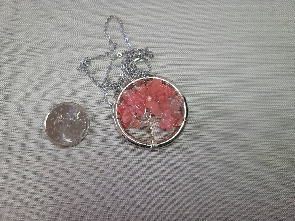 Necklace with pink stone pendant next to a quarter on a gray background