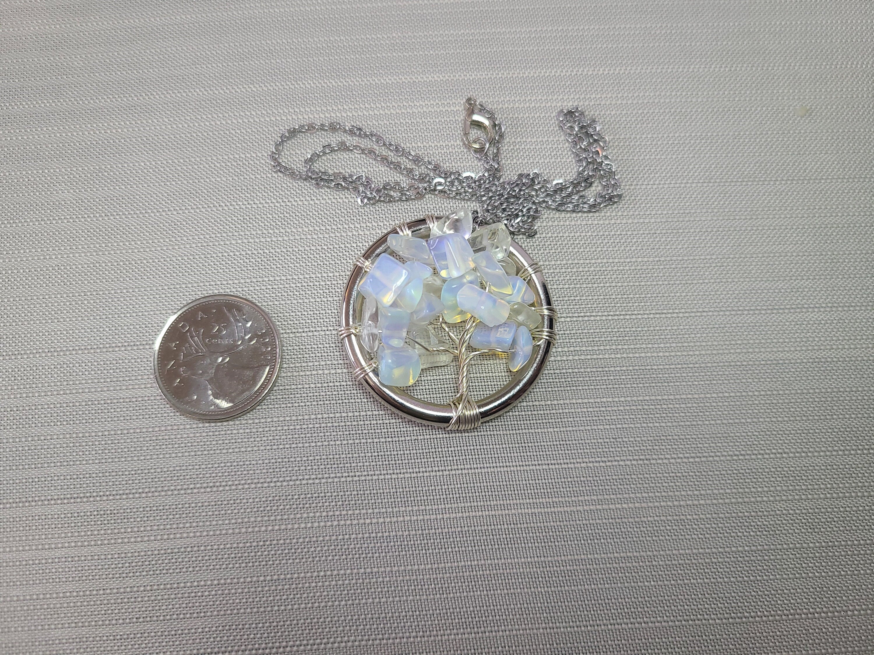 Opalite tree of life pendant with chain on a gray background