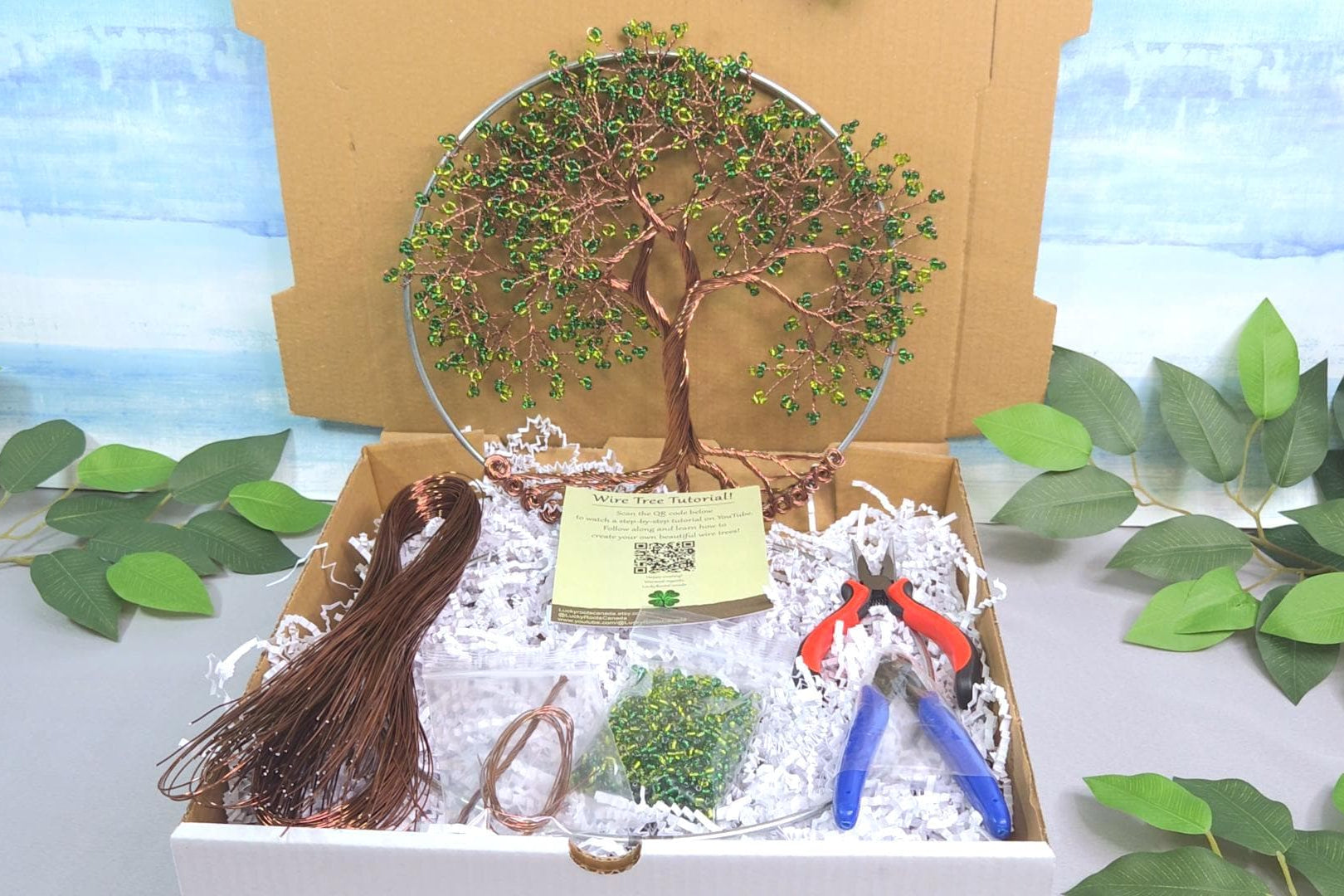 Box with a tree ornament, tassel, and tools on a scenic background