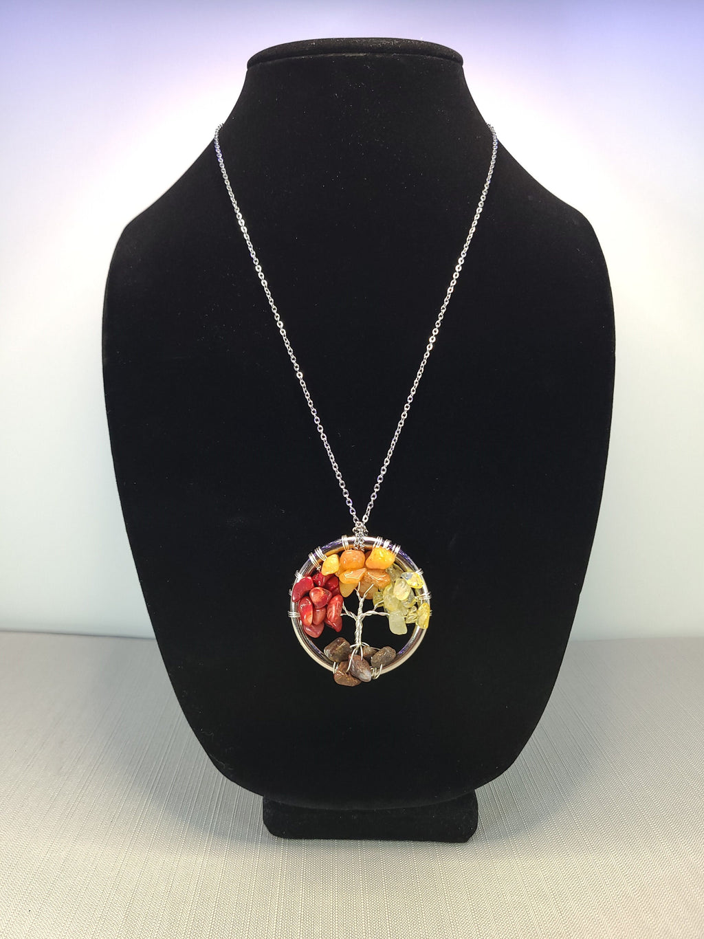 Necklace with a colorful pendant on a black bust against a white background