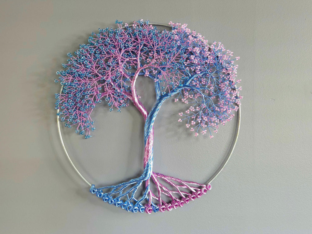 Decorative wall art of a tree with pink and blue branches on a plain background