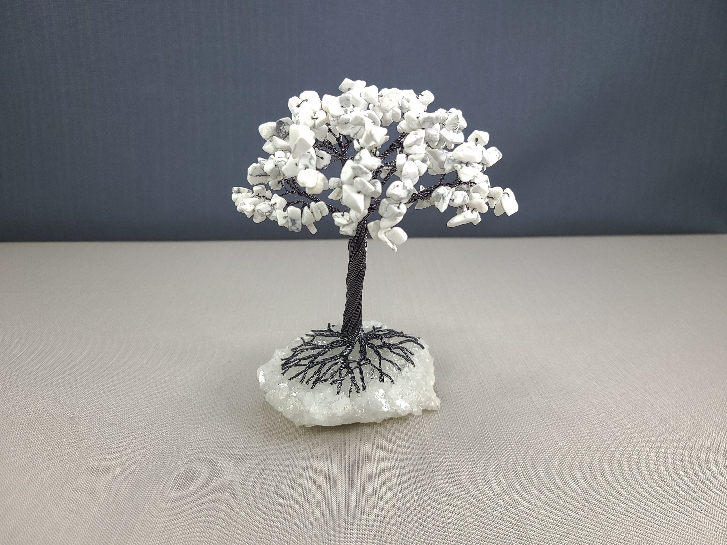 Small tree sculpture with white flowers on a gray surface and dark background