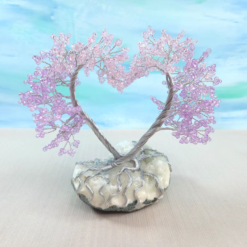 Decorative tree with pink beads on a stone base against a light blue background