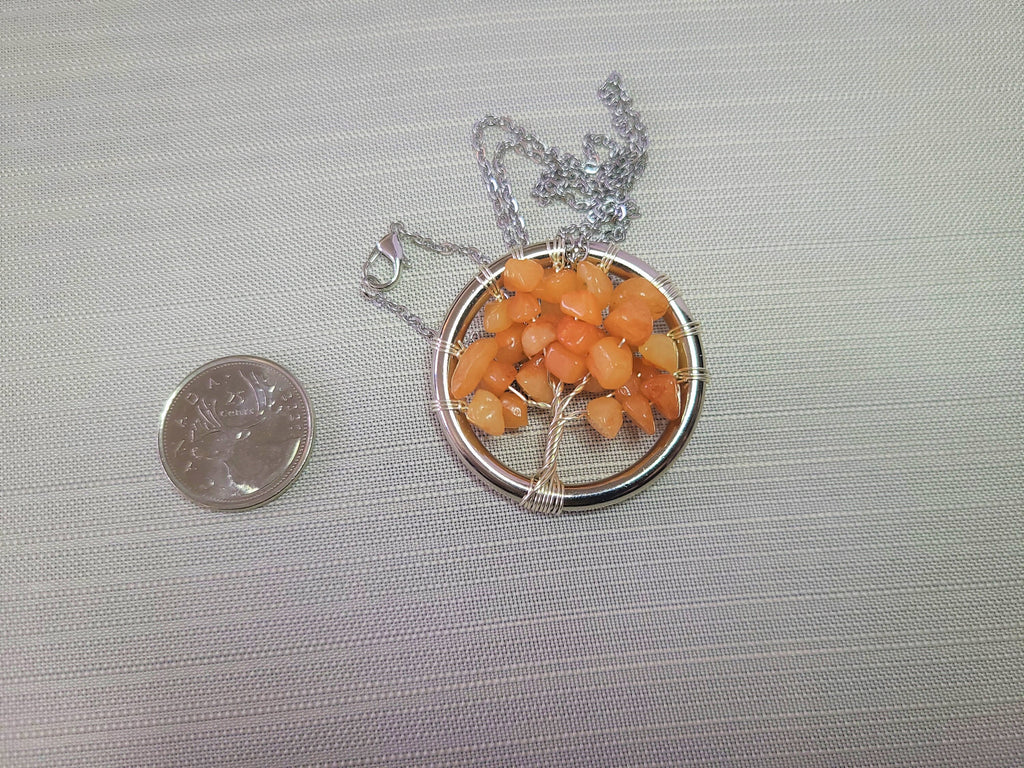 Necklace with a tree-shaped pendant made of orange beads on a gray background.