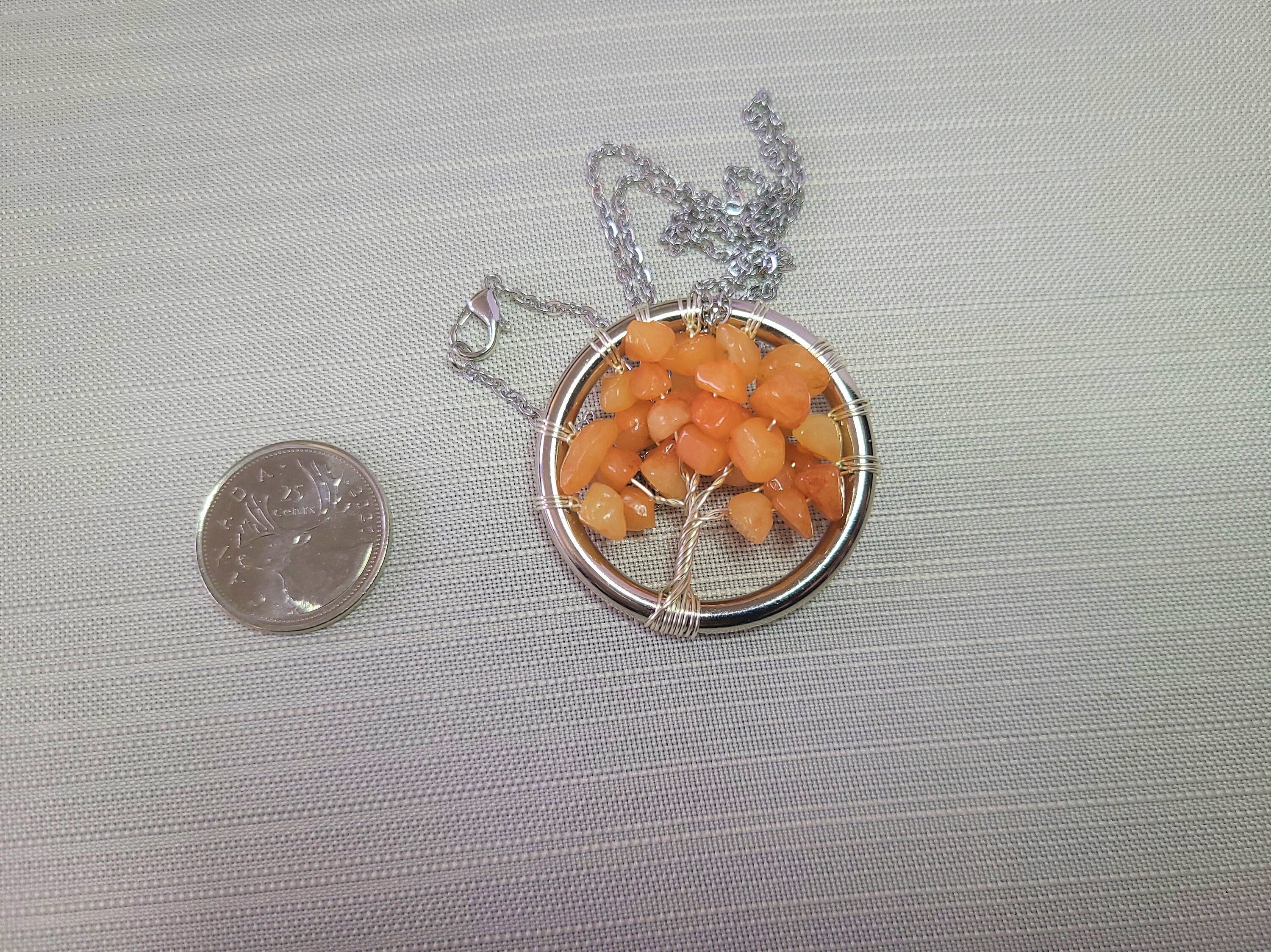 Necklace with a tree-shaped pendant made of orange beads on a gray background.