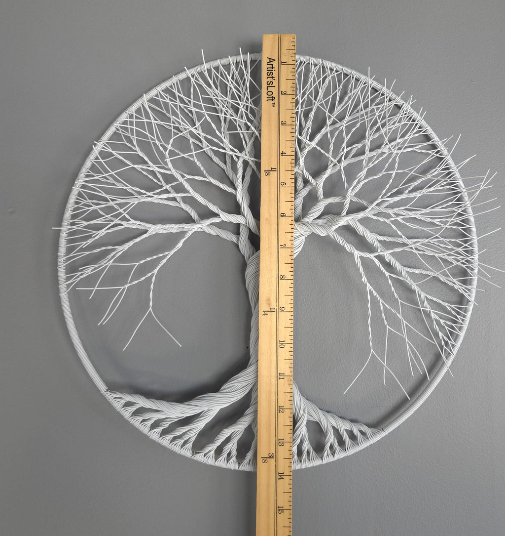 Circular wall art with tree branches design, measured by a ruler on a gray background