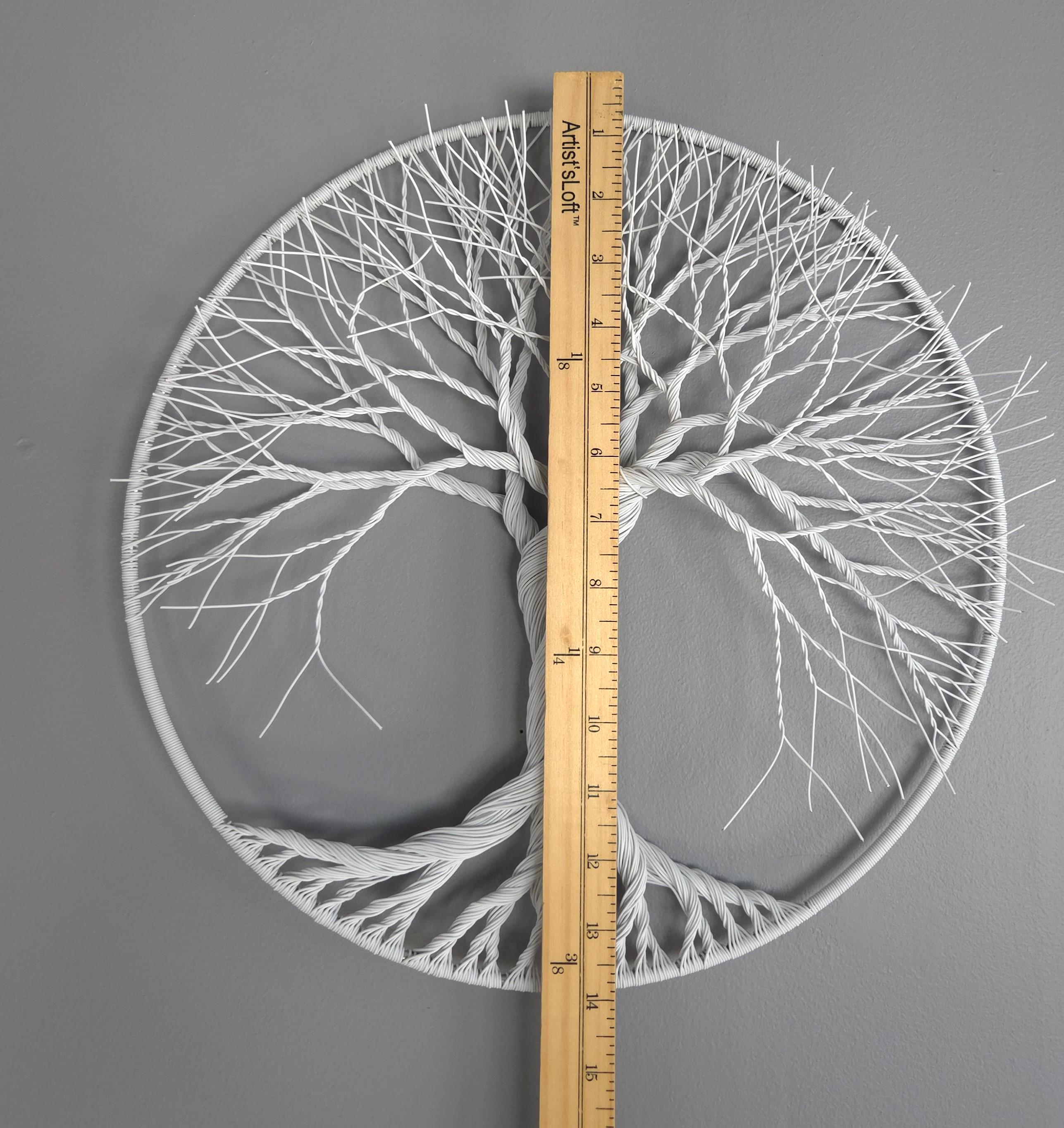 Circular wall art with tree branches design, measured by a ruler on a gray background
