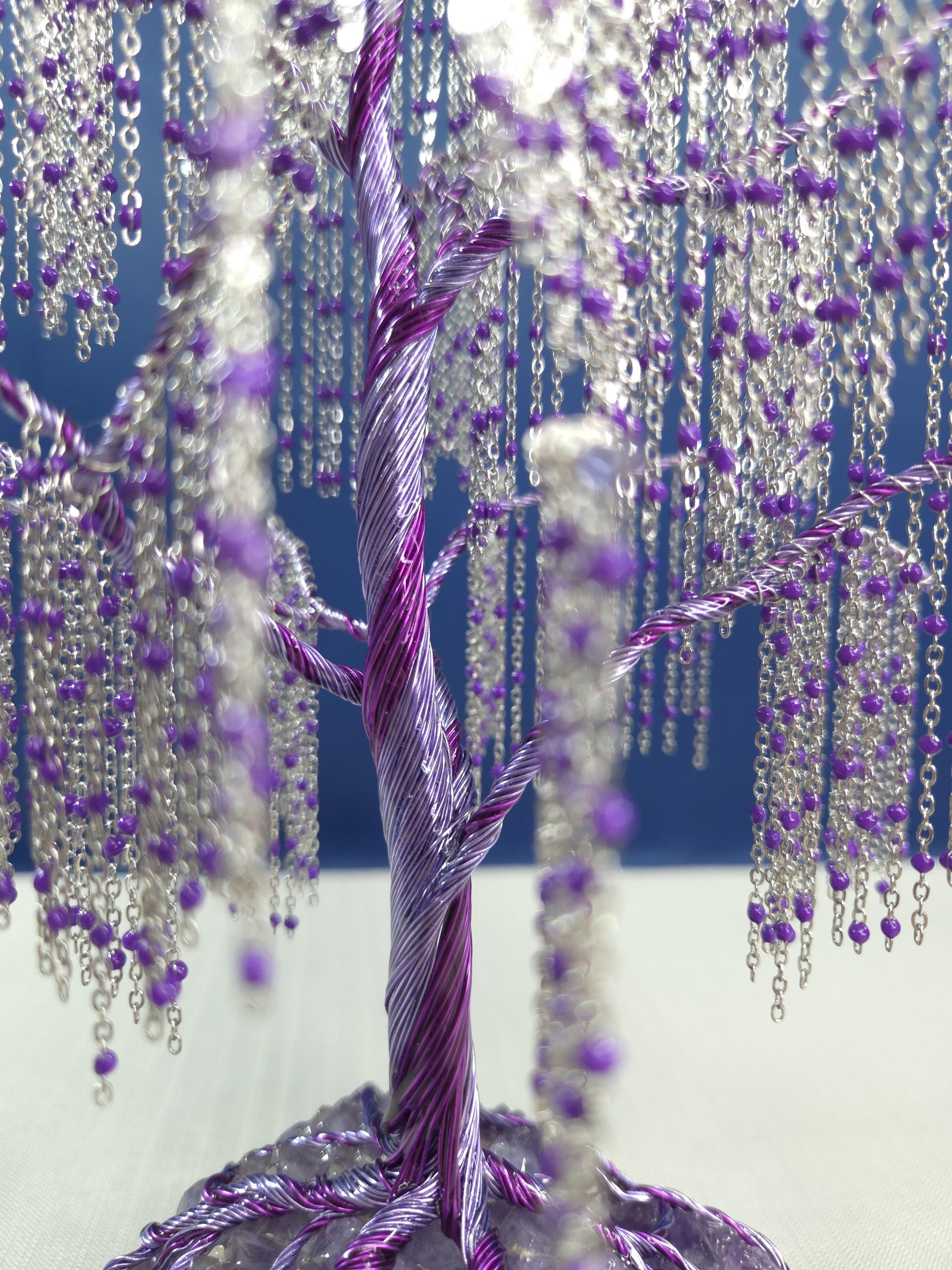 Decorative tree made of purple and silver beads against a blue background