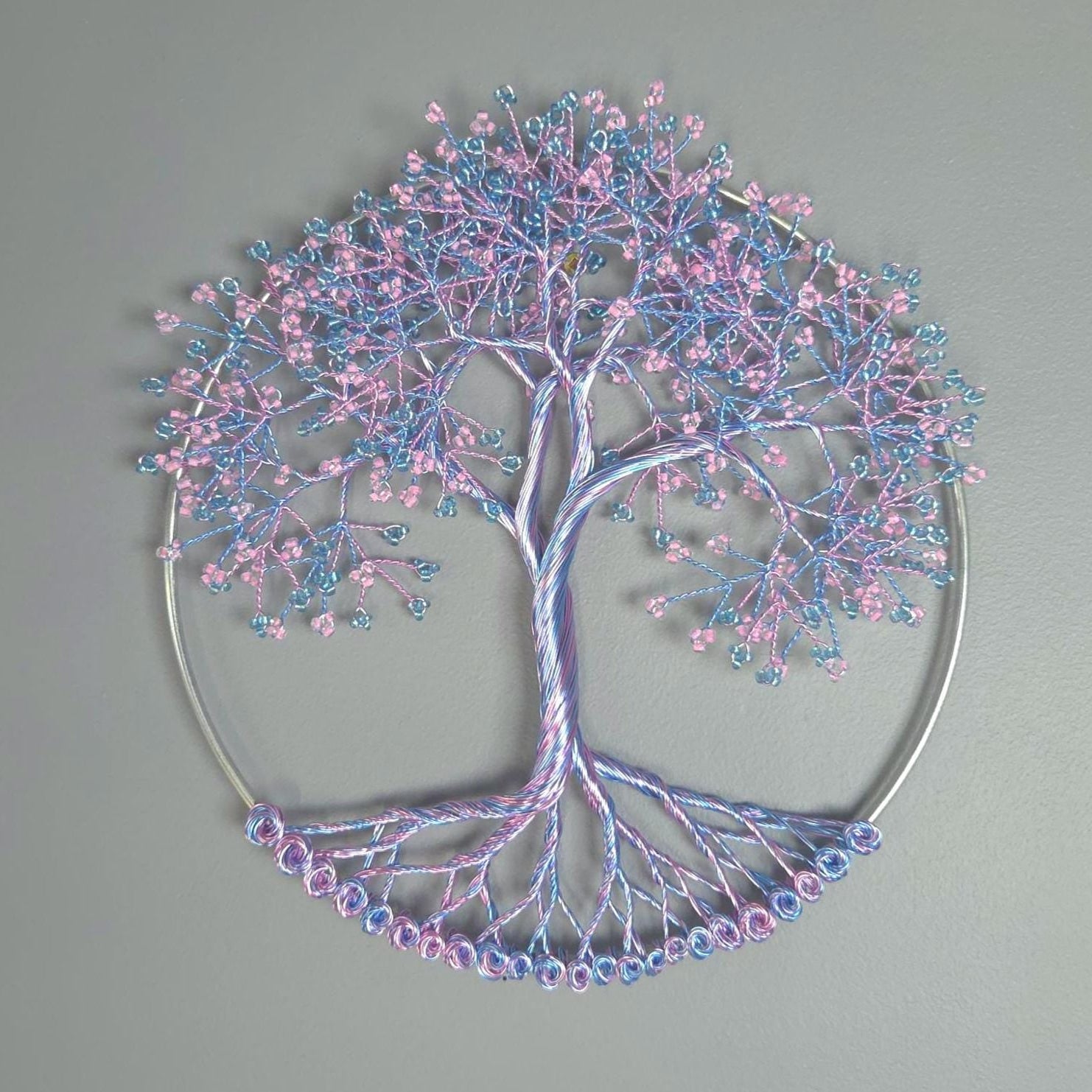 Decorative tree wall art with pink and blue branches on a gray background