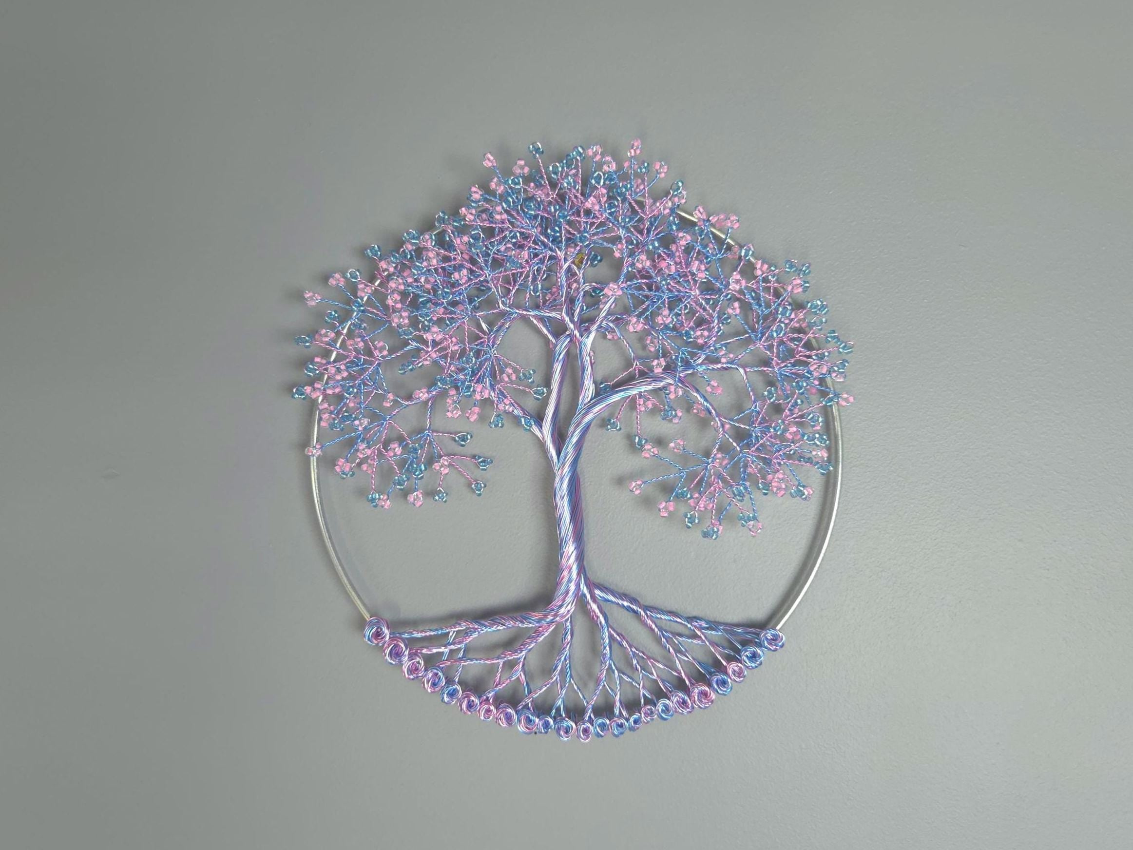 Decorative tree wall art with pink and blue branches on a gray background