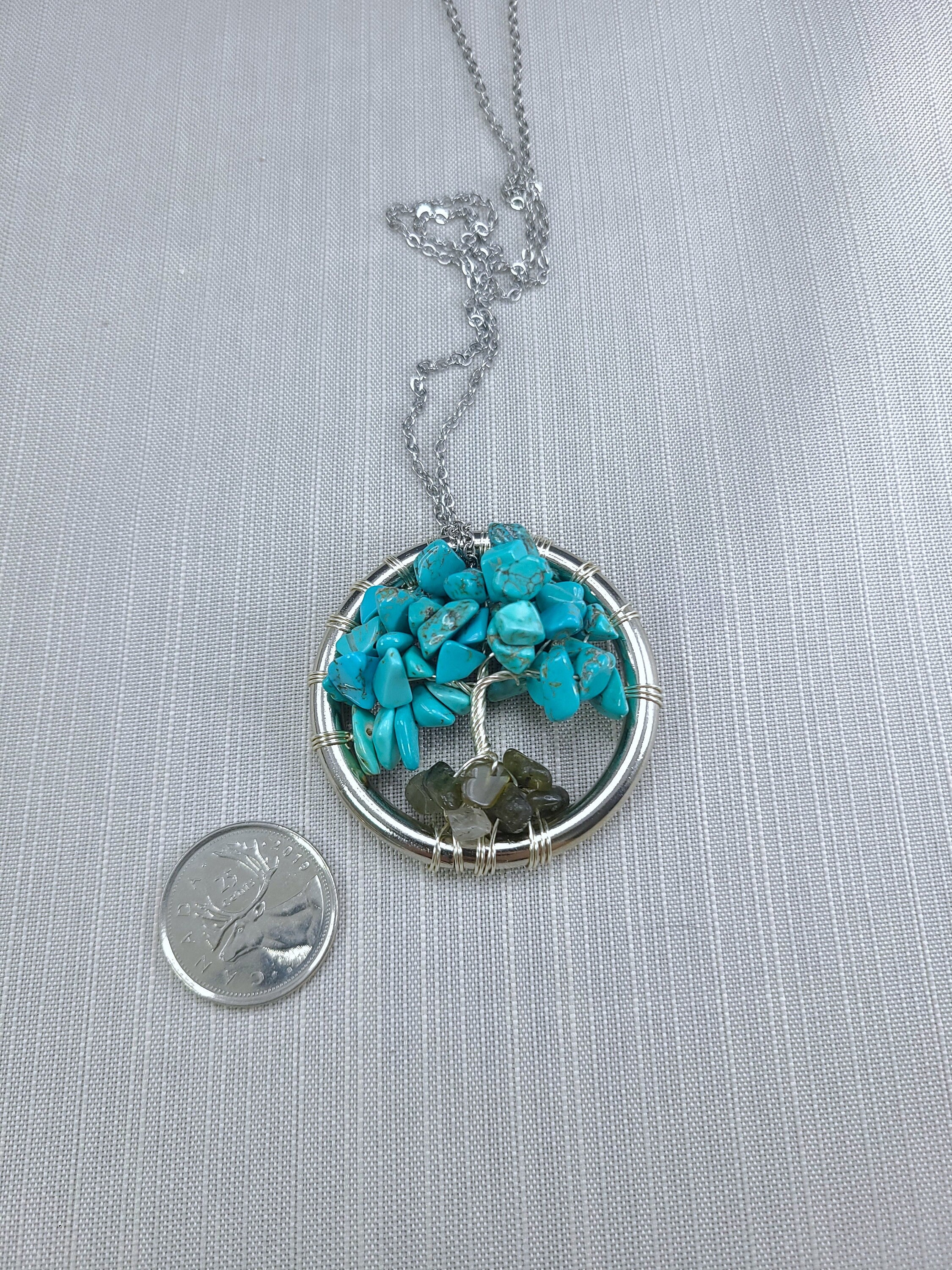 Necklace with turquoise and green stone pendant next to a coin on a gray background