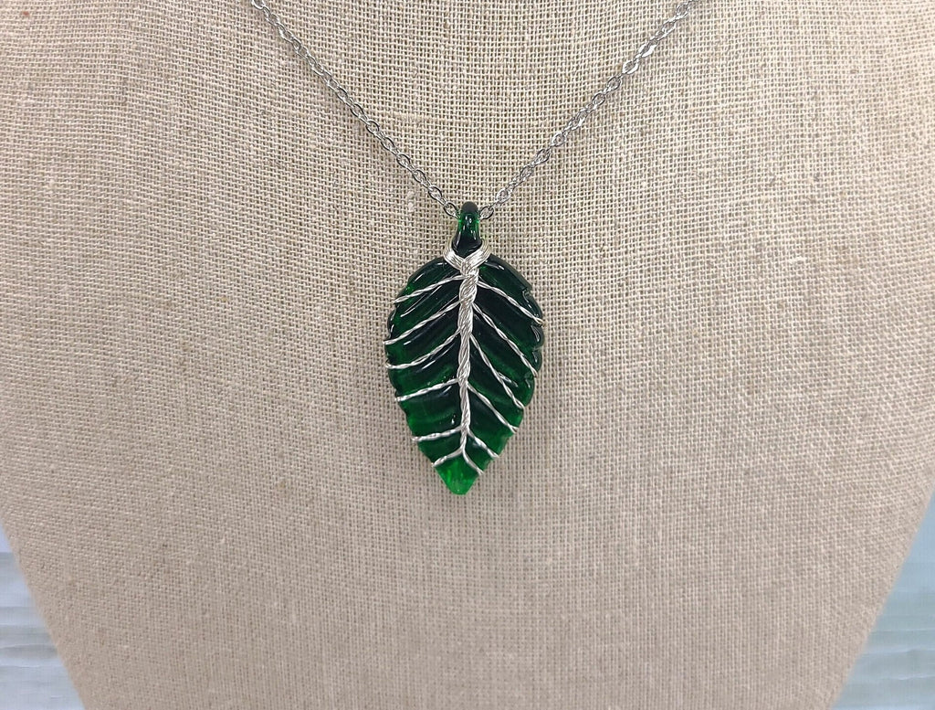 Leaf-shaped pendant necklace on a beige surface