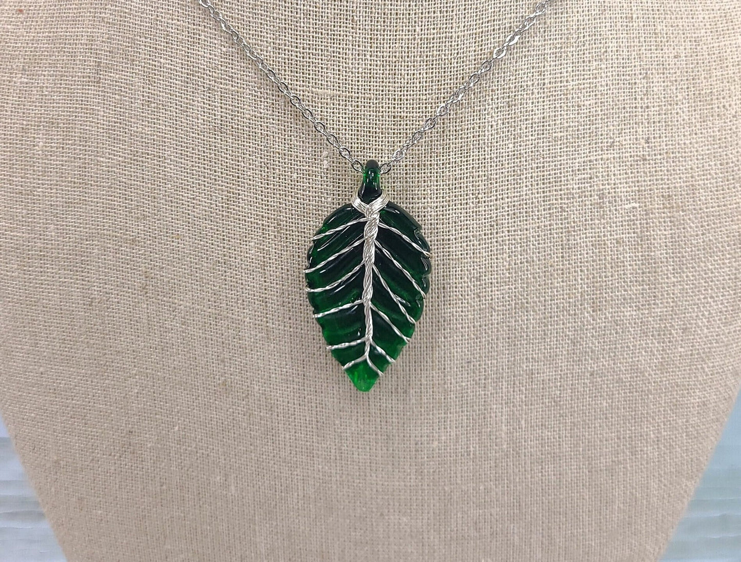 Leaf-shaped pendant necklace on a beige surface