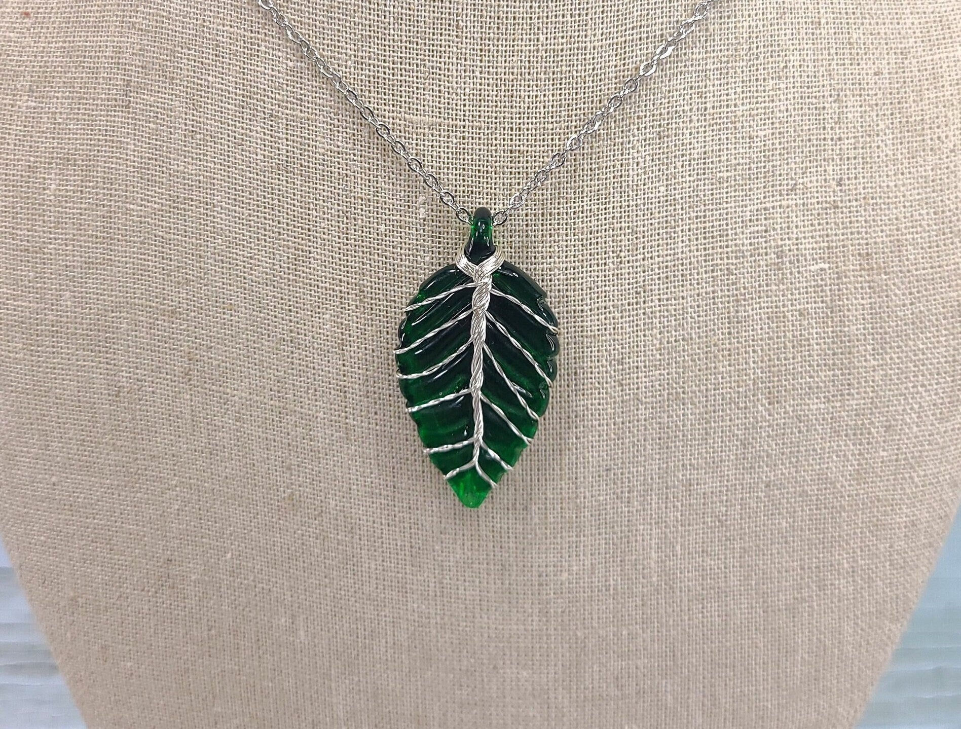Leaf-shaped pendant necklace on a beige surface