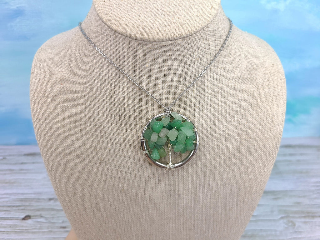 Necklace with a green pendant on a mannequin bust against a blurred natural background