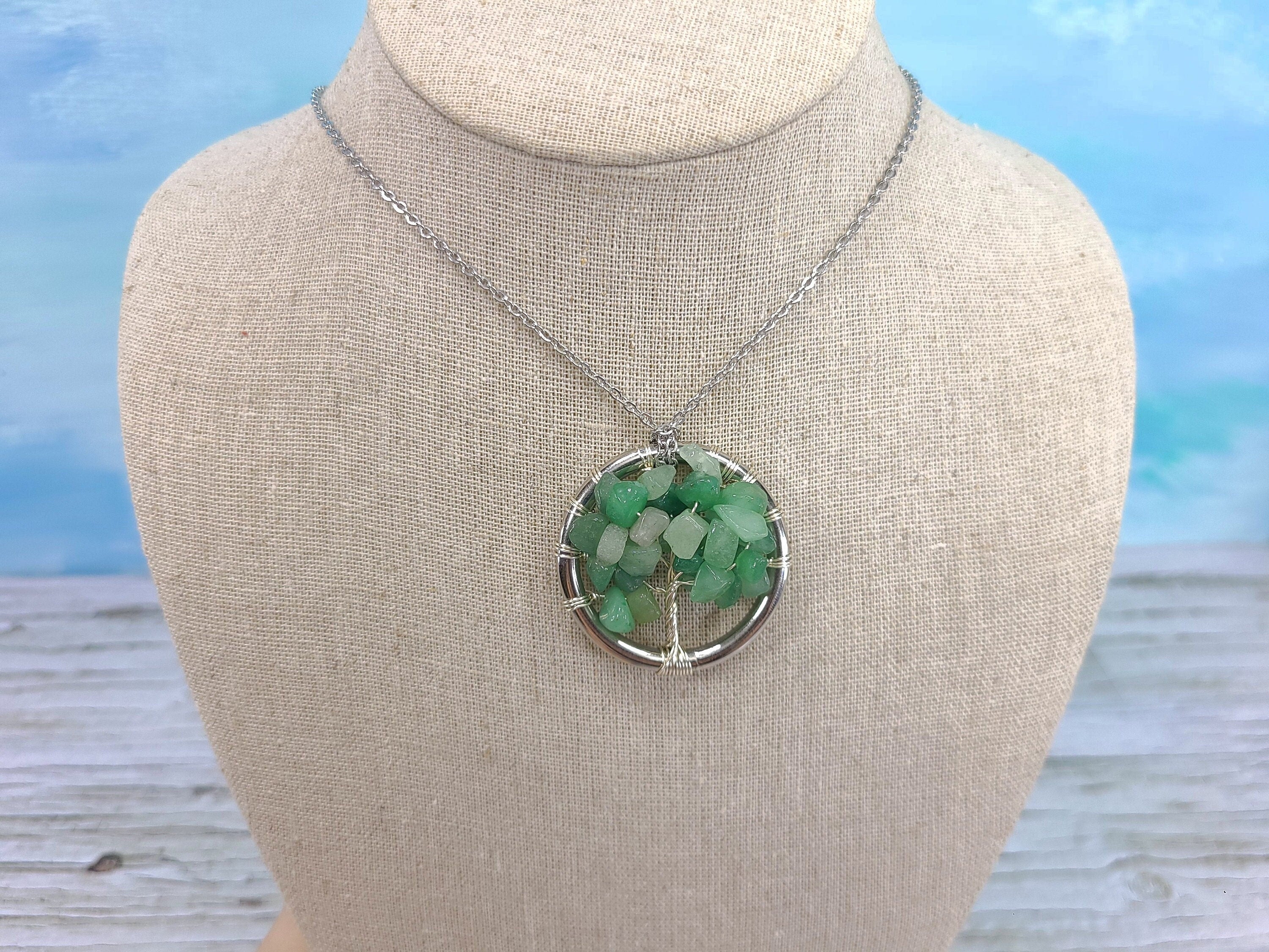 Necklace with a green pendant on a mannequin bust against a blurred natural background