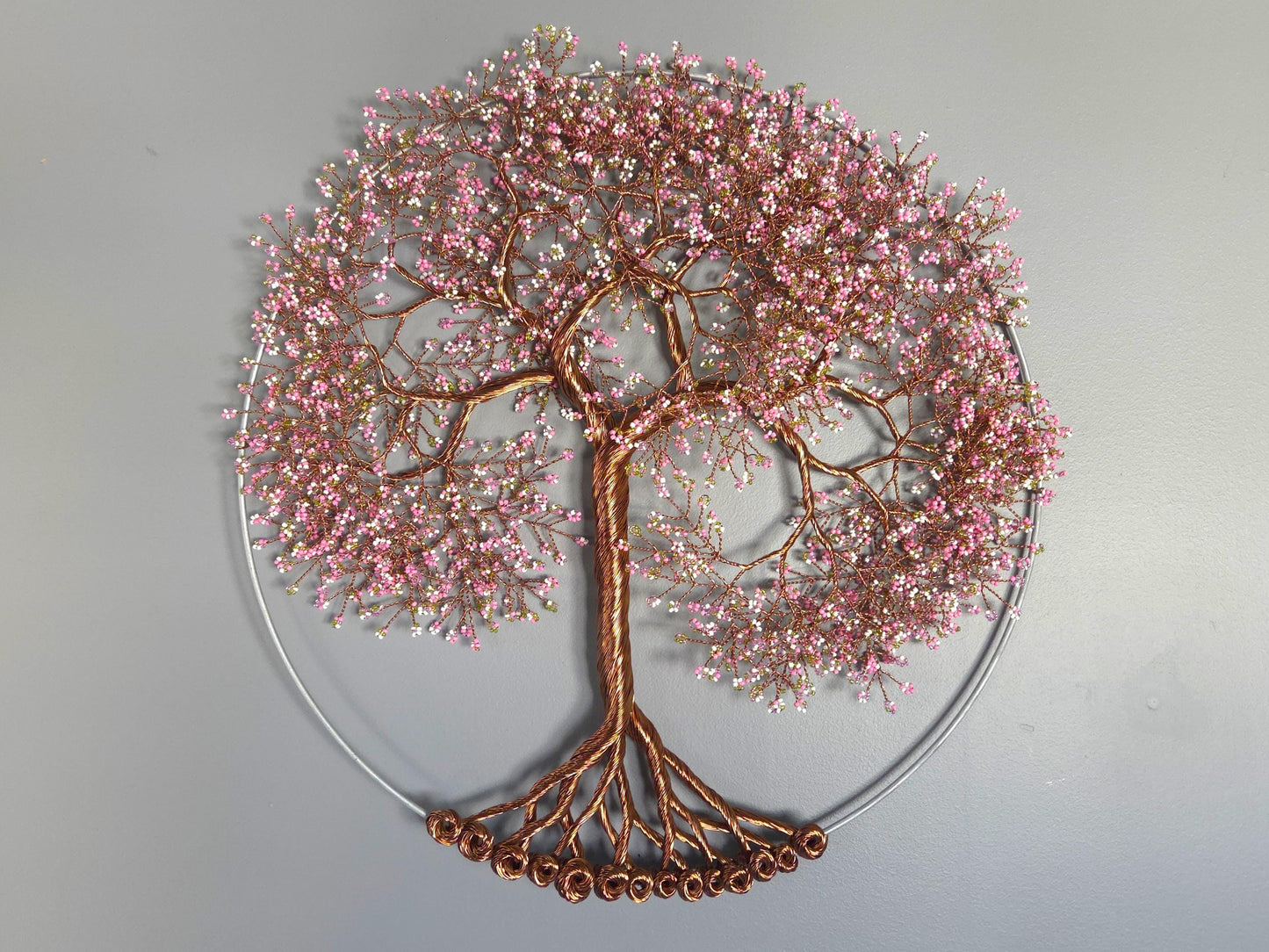 Decorative wall art of a tree with pink blossoms and copper branches on a gray background