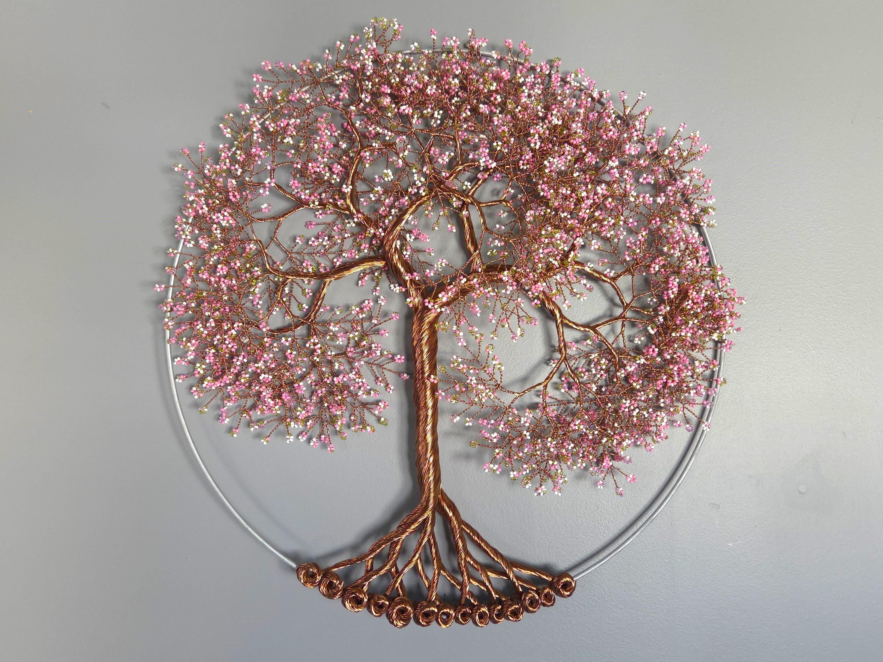 Decorative wall art of a tree with pink blossoms and copper branches on a gray background