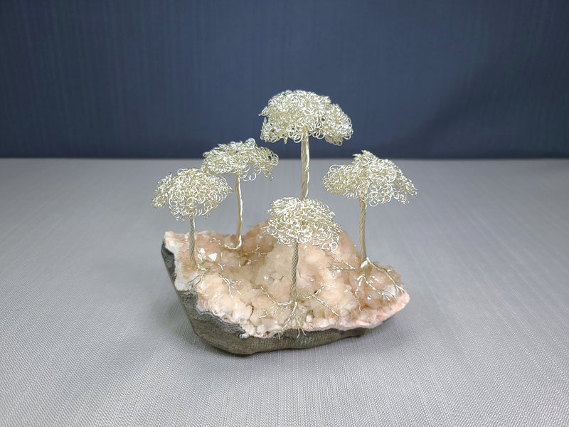 Decorative sculpture of wire trees on a rock base with a blue background