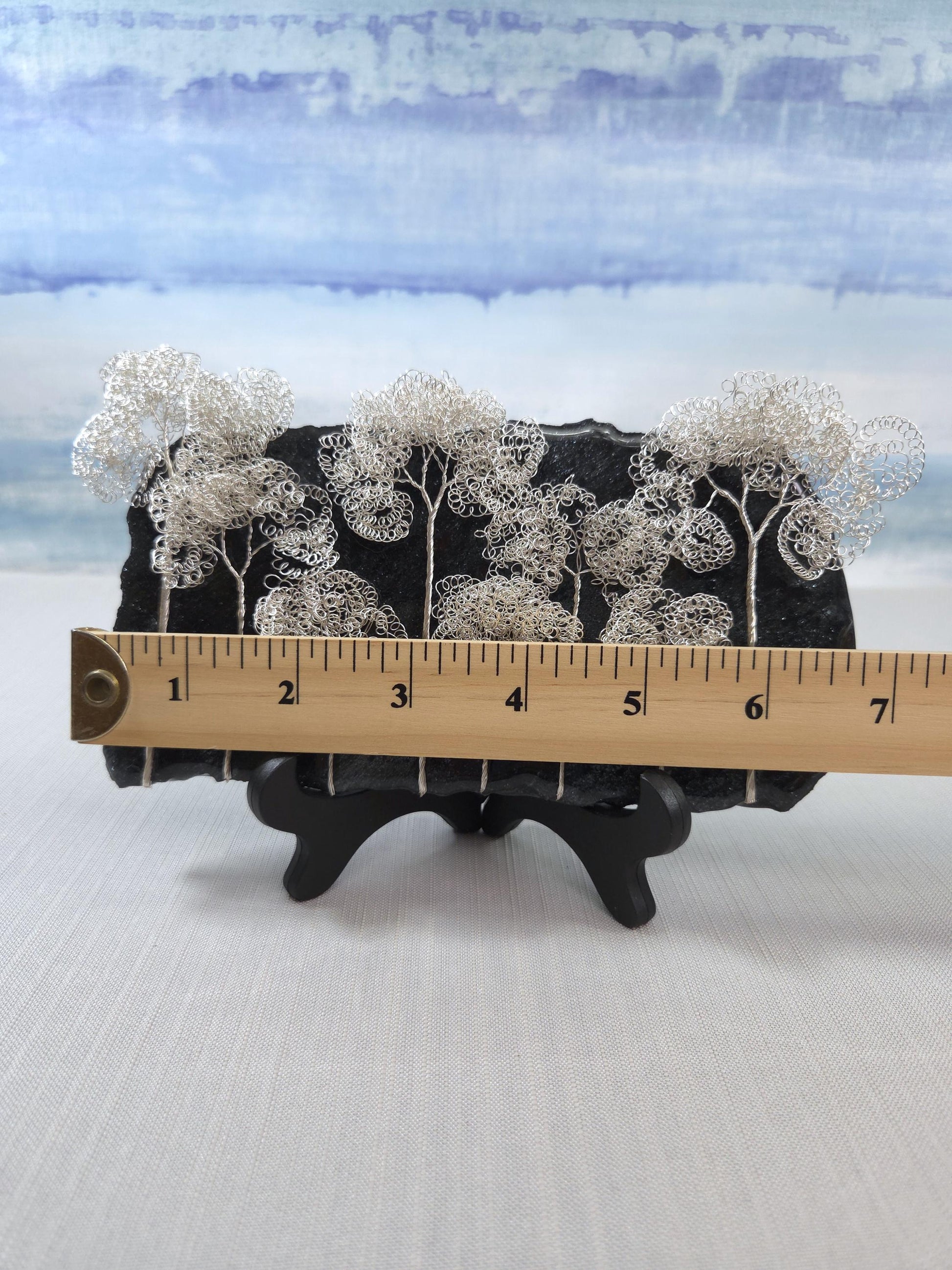 Decorative item with silver trees on a black base, measured against a ruler.