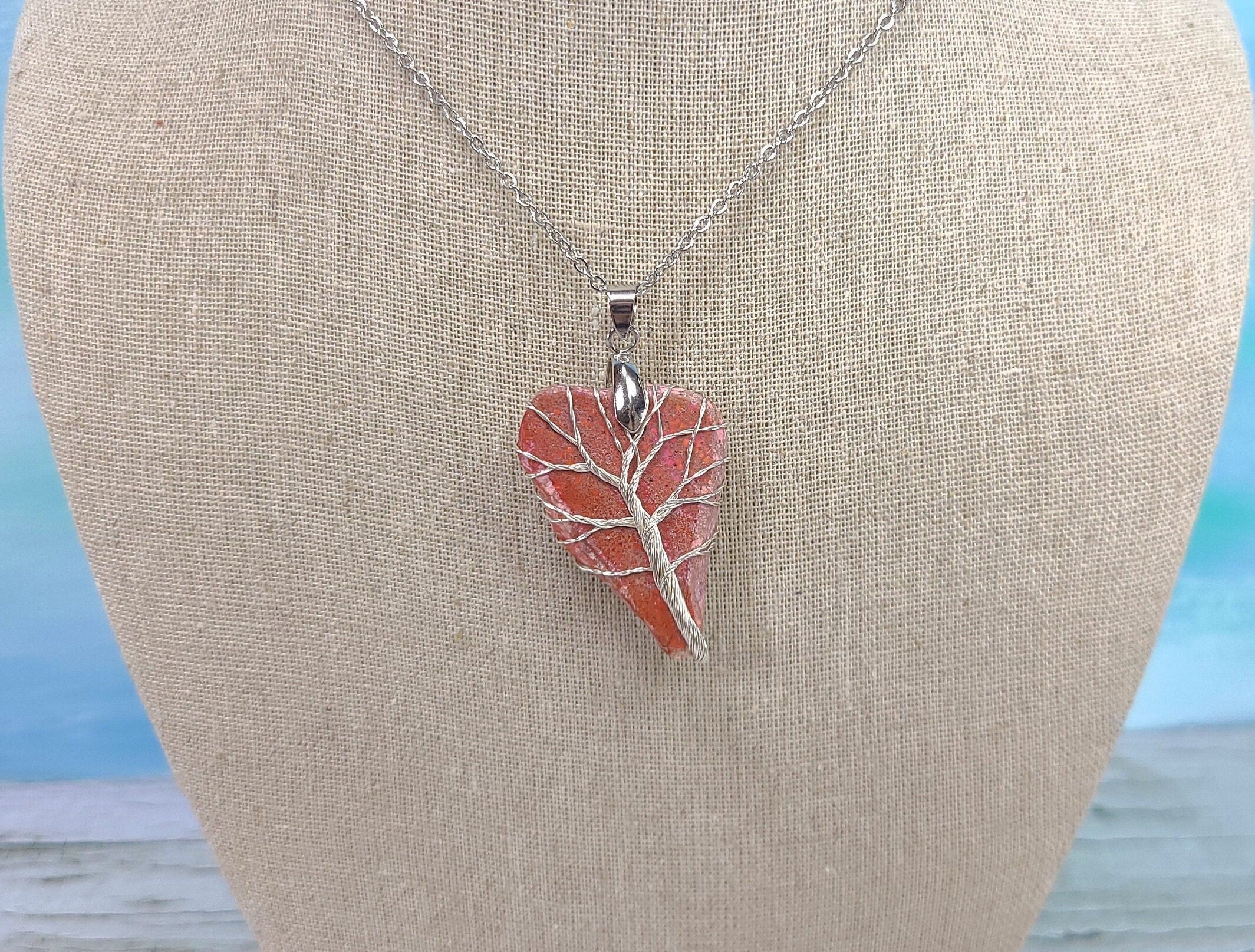 Necklace with a red leaf-shaped pendant on a mannequin bust.