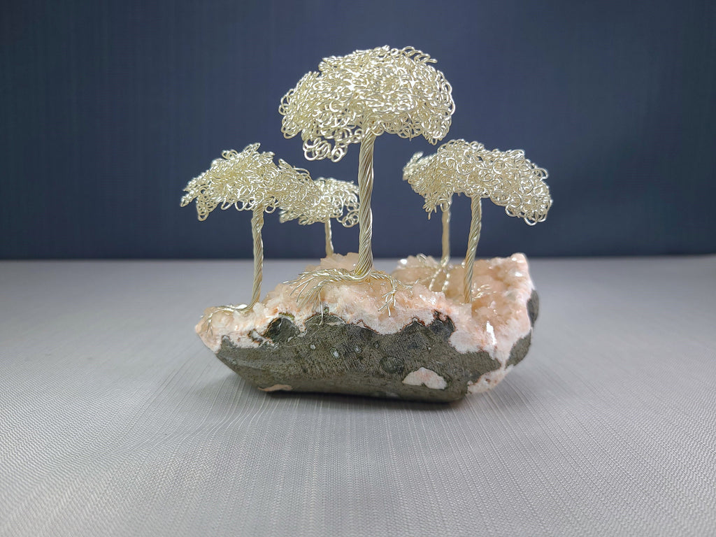 Decorative wire tree sculpture on a natural stone base with a dark blue background