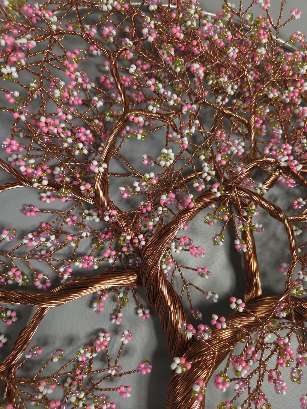 Decorative wire tree with pink and green beads on a gray background