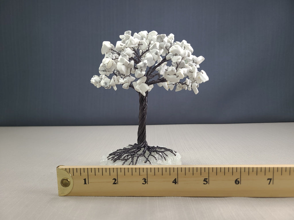 Small model tree with white flowers on a gray background, next to a ruler for scale.