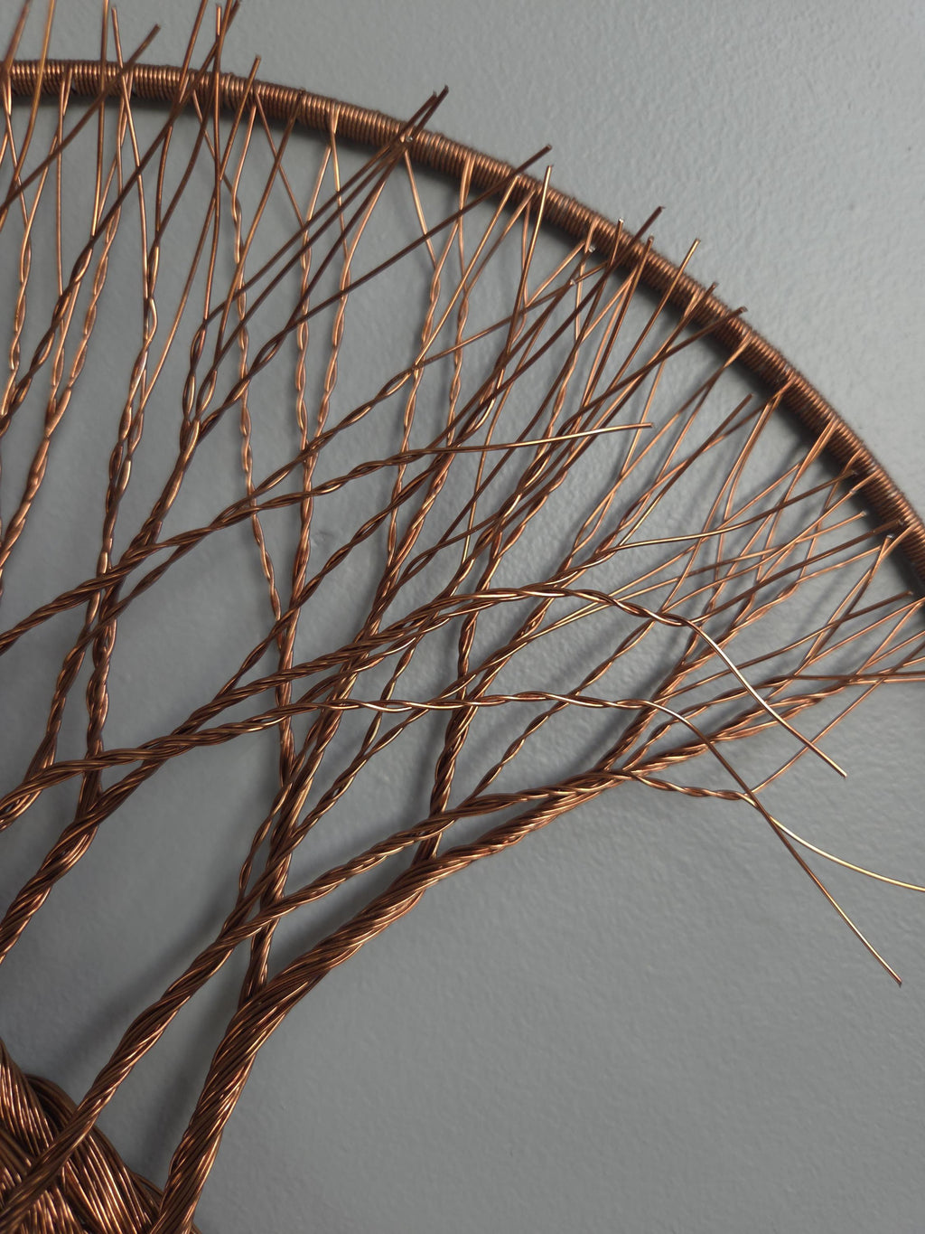 Decorative wall art made of interwoven branches on a gray background