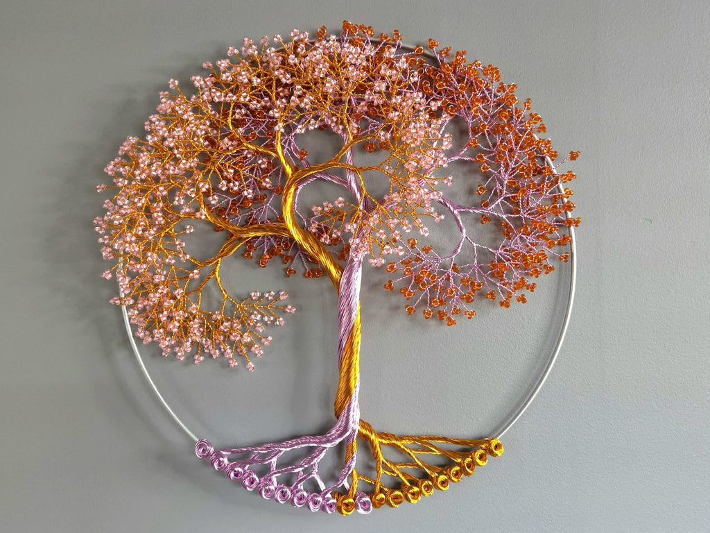 Decorative wall art of a tree with pink and orange leaves on a gray background