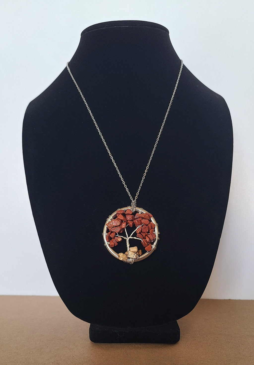 Necklace with a circular pendant on a black bust against a white background