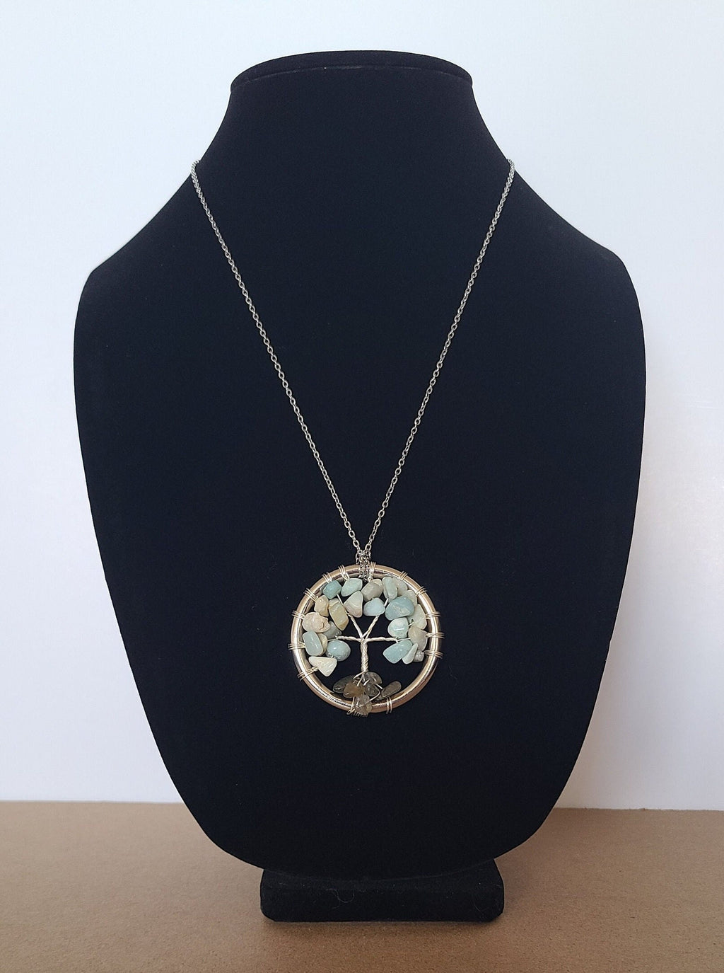 Necklace with a circular pendant on a black velvet stand against a white background
