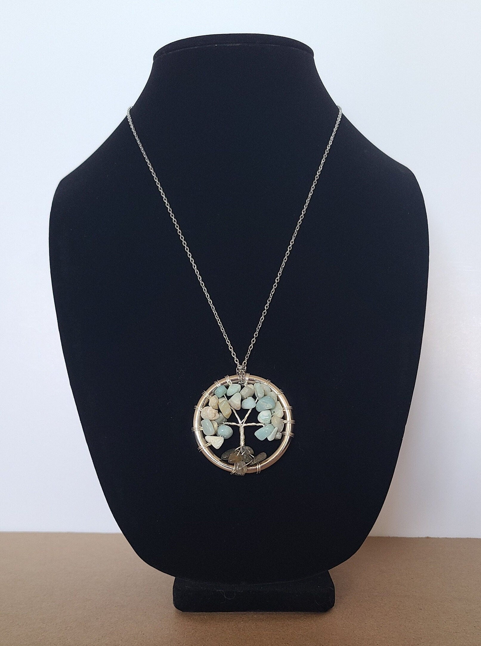 Necklace with a circular pendant on a black velvet stand against a white background