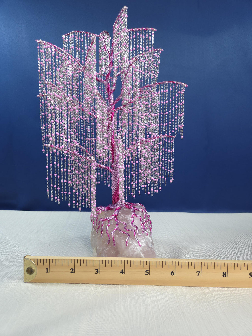 Decorative pink beaded tree with a ruler for scale against a blue background