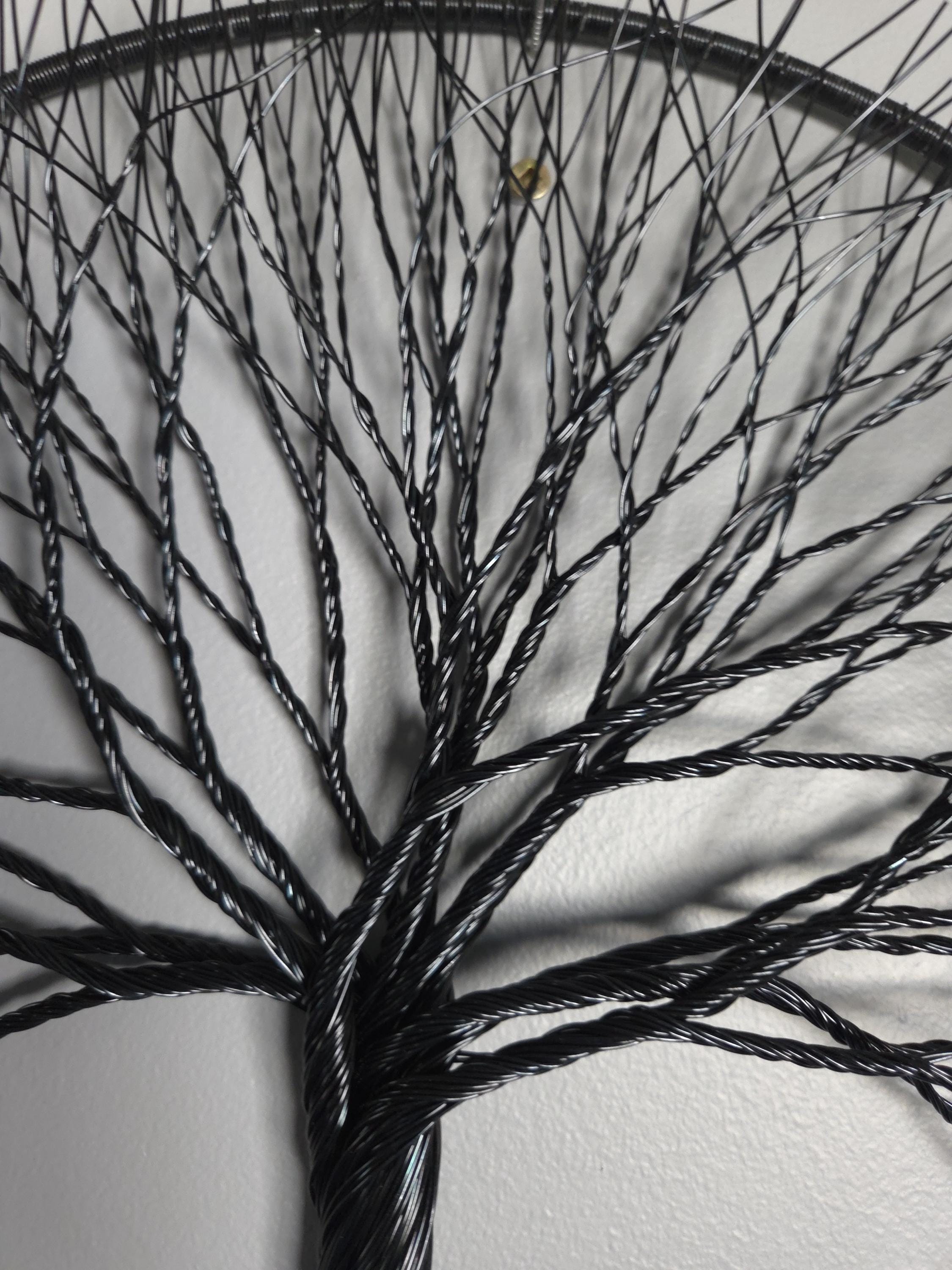 Artistic depiction of a tree made from thin black wires on a white background