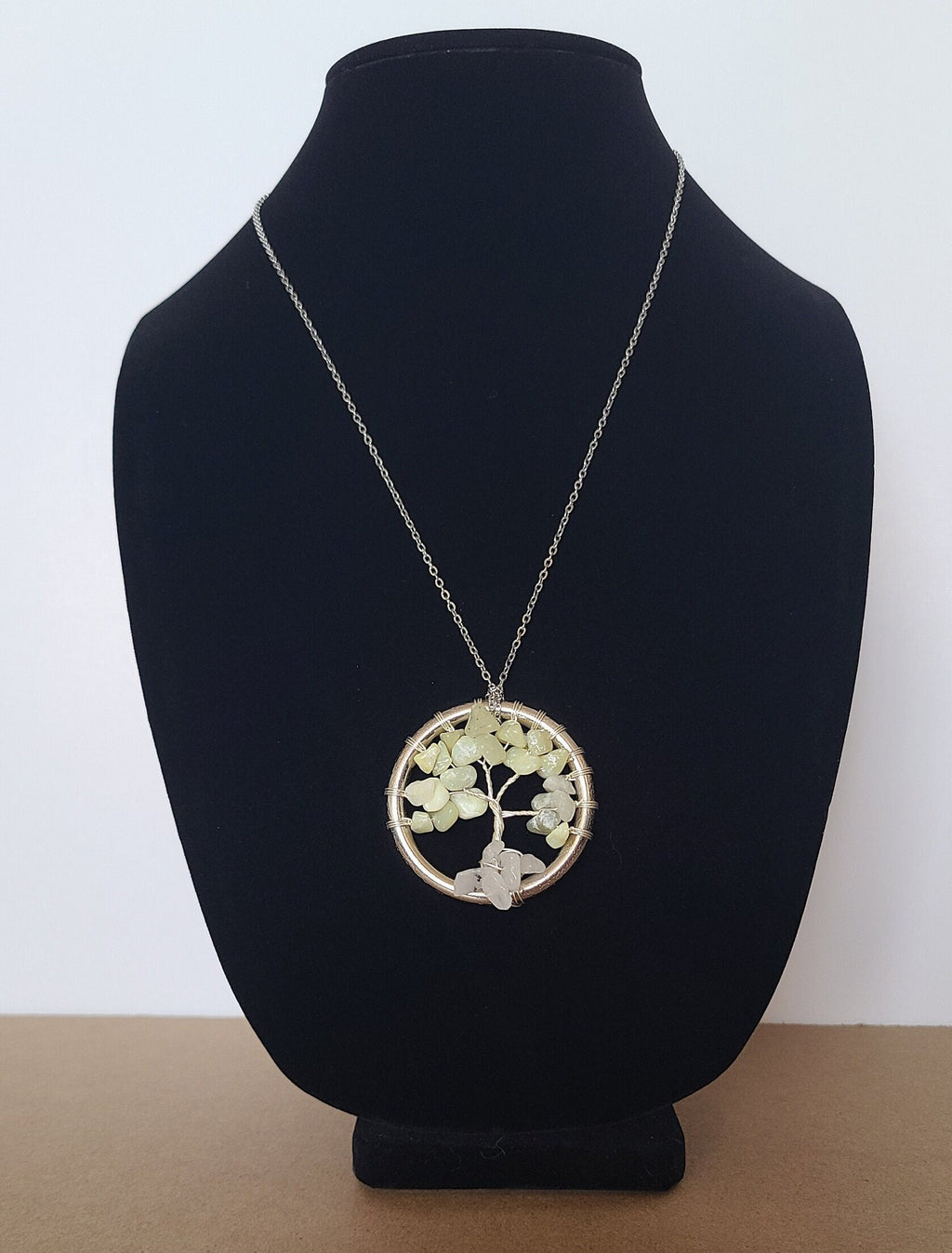 Necklace with a circular pendant on a black bust against a white background