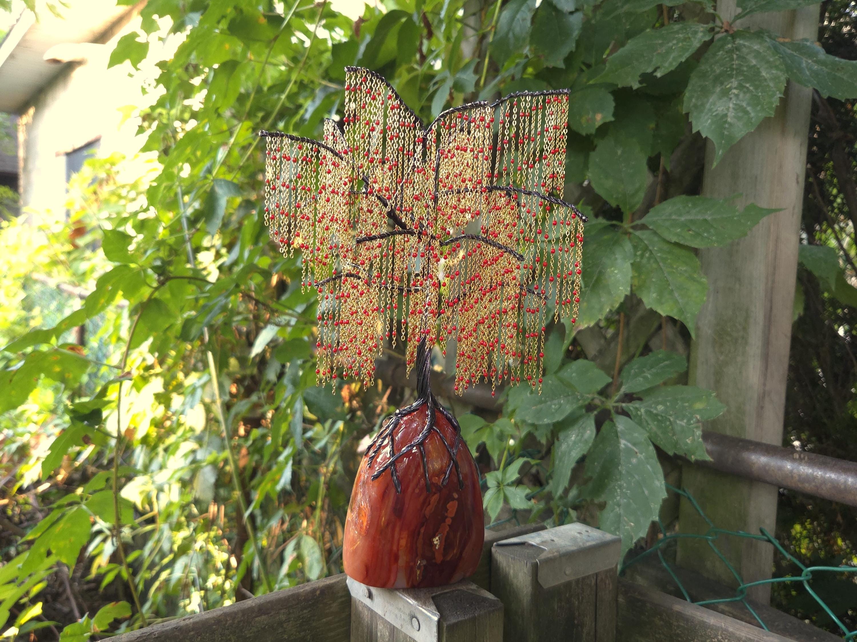 Decorative willow sculpture on a wooden post with green foliage in the background