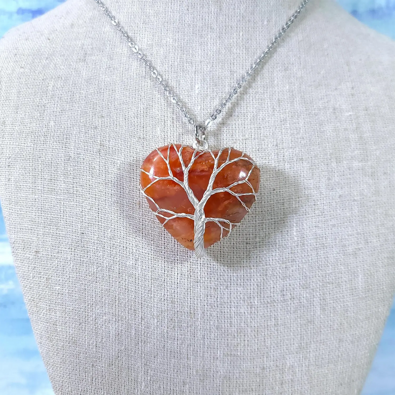 Heart-shaped stone pendant with silver tree design on a mannequin bust against a light background