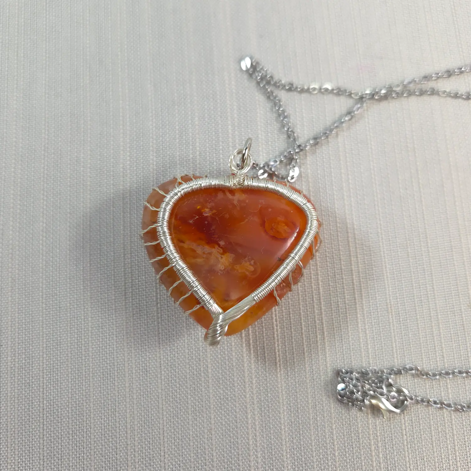 Heart-shaped amber pendant on a silver chain against a light background